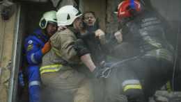 Ukrajinskí hasiči nesú zranenú ženu z ruín obytnej budovy v ukrajinskom meste Dnipro.