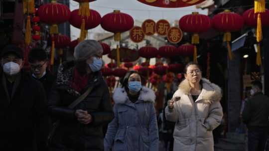 Ľudia s rúškami v uliciach Pekingu.