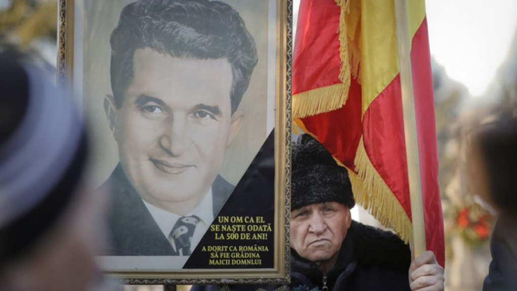 Muž drží vlajku a obraz s podobizňou Nicolae Ceaušesca, archívna snímka.