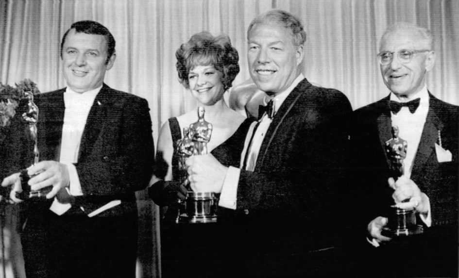 Na snímke z roku 1968 zľava americkí herci Rod Steiger, Estelle Parsons, George Kennedy a režisér George Cukor, ktorý prevzal Oscara za herečku Katherine Hepburnovú.