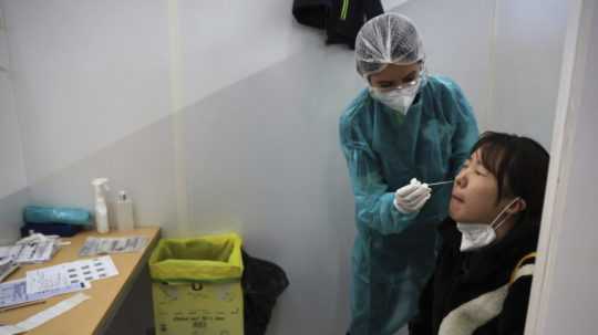 Zdravotníčka testuje cestujúcu prichádzajúcu z Číny na ochorenie COVID-19 v testovacej kabínke na letisku Charlesa de Gaulla pri Paríži.