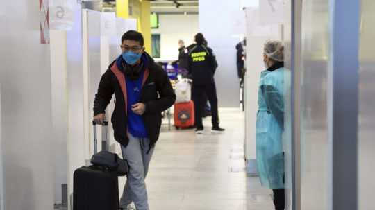 Cestujúci prichádzajúci z Číny odchádza po teste na ochorenie COVID-19 z testovacej kabínky na letisku Charlesa de Gaulla pri Paríži.