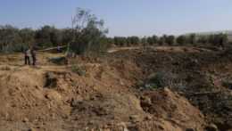 a snímke ľudia sledujú jamu v zemi a zničené olivové stromy vo vojenskom tábore hnutia Hamas, ktorý sa nachádza v utečeneckom tábore Maghazi v pásme Gazy 4. novembra 2022.