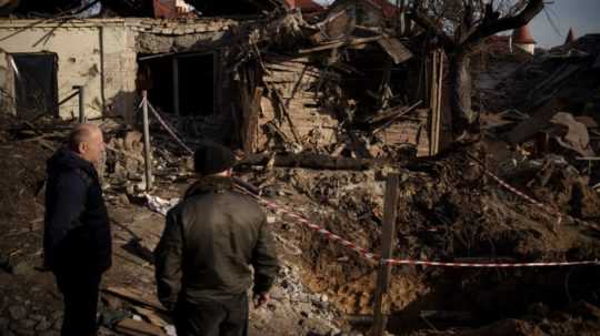Na ilustračnej snímke dvaja muži pozerajú na budovy zničené bombardovaním.