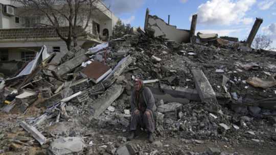 Na archívnej snímke žena sedí na troskách budovy, ktorá sa zrútila v dôsledku zemetrasenia v meste Nurdagi na juhu Turecka.