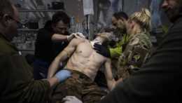 Ukrajinskí vojenskí zdravotníci ošetrujú svojho zraneného muža v poľnej nemocnici pri Bachmute na Ukrajine.