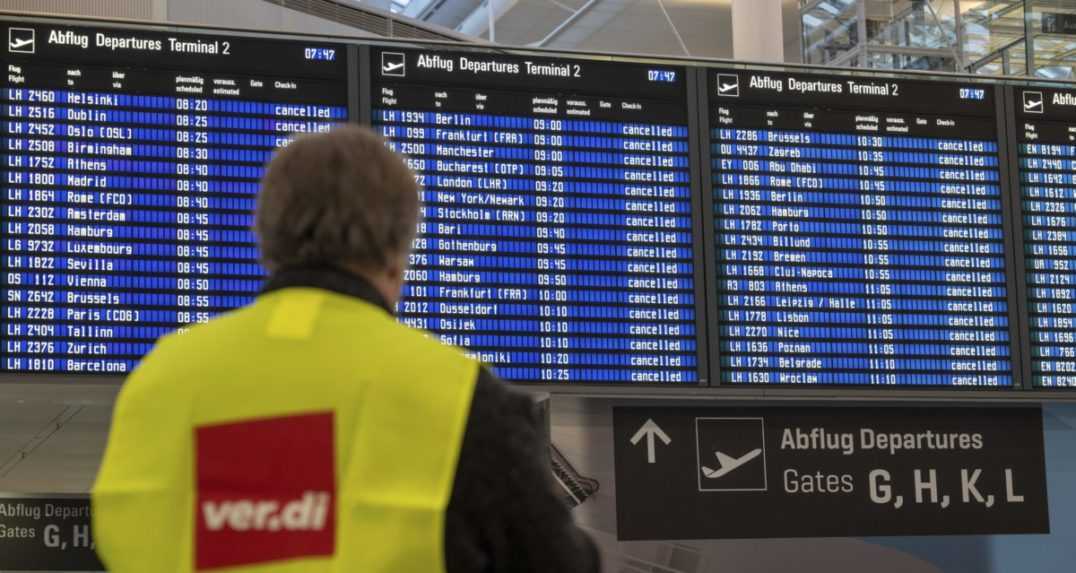 Zamestnanec frankfurtského letiska stojí pred tabuľou so zrušenými letmi.