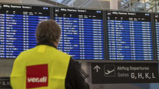 Zamestnanec frankfurtského letiska stojí pred tabuľou so zrušenými letmi.