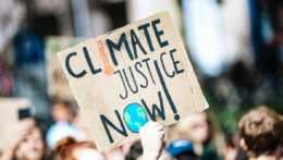 Transparent s nápisom "Klimatickú spravodlivosť teraz".
