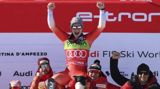 Švajčiarsky lyžiar Marco Odermatt (hore uprostred) oslavuje na pódiu so svojím tímom po jeho víťazstve pretekov super-G Svetového pohára v alpskom lyžovaní.