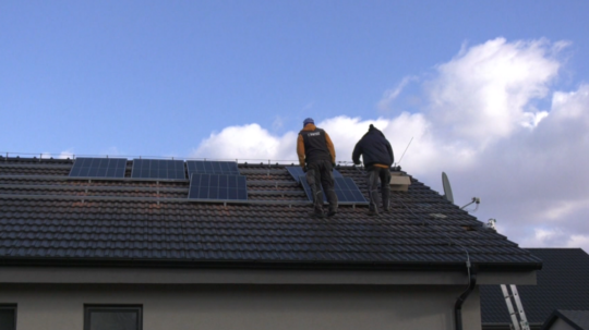 Pracovníci inštalujú na streche domu solárne panely.