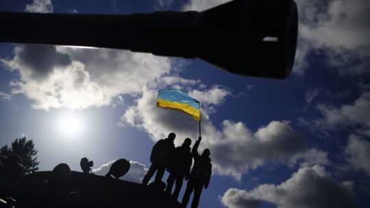 Na snímke ukrajinskí vojaci s ukrajinskou vlajkou.