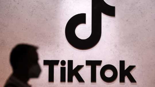 Logo siete TikTok a v popredí vľavo silueta osoby.