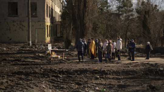 Kňaz slúži bohoslužbu na pamiatku obetí na mieste budovy, ktorú silno poškodil nálet a bola pred rokom zbúraná v ukrajinskom meste Boroďanka.