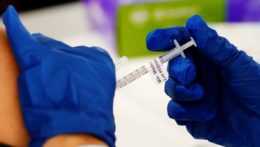 Na snímke osoba podáva vakcínu injekčnou striekačkou.