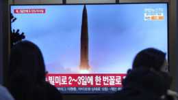 Ľudia sledujú archívne zábery severokórejskej rakety počas vysielania správ na železničnej stanici v Soule.
