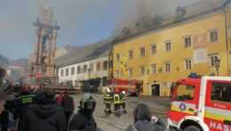Horiaca žltá budova Banského múzea v Banskej Štiavnici, z ktorej stúpa dym a požiarnici na ňu striekajú prúd vody.