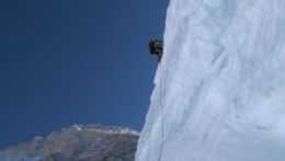 Na snímke horolezec zdoláva ľadovú stenu v pozadí hory