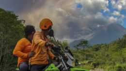 Muži sledujú erupciu sopky Merapi v indonézskom meste Sleman.