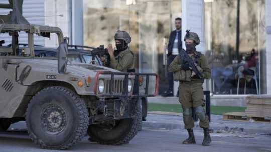Na snímke izraelskí vojaci so zbraňami v rukách a kuklami na tvárach.