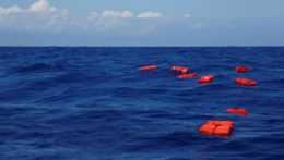 na ilustračnej snímke plávajú na mori oranžové záchranné vesty