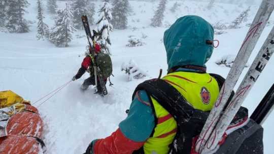 Na snímke záchranári brodiaci sa snehom s lyžami na chrbte