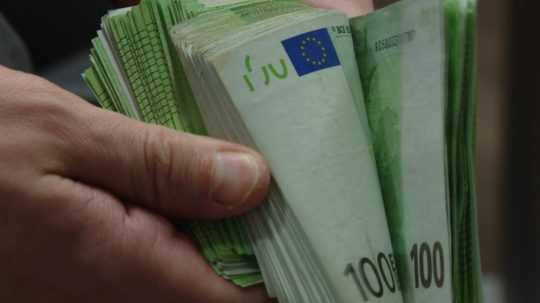 Na sníme osoba drží zväzok sto-eurových bankoviek.