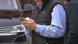 Na snímke starší muž pozerá do mobilného telefónu.