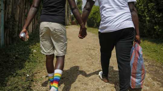 Dvaja ugandskí muži sa držia za ruky.