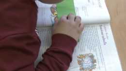 Na snímke žiak číta zo šlabikára.