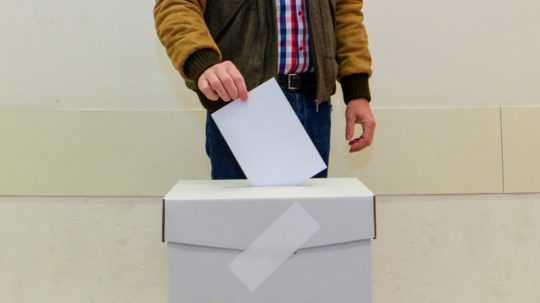 Na snímke osoba vhadzuje obálku do volebnej urny.