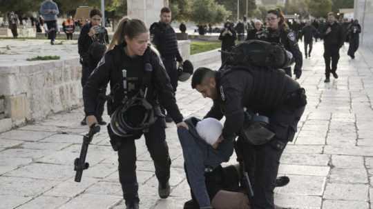 Izralský policajt a policajtka zatýkajú Palestínčanku po razii v komplexe mešity al-Aksá.