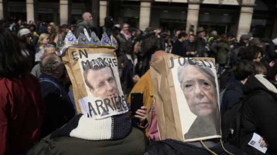 Demonštranti v maskách s portrétom francúzskeho prezidenta Emmanuela Macrona a francúzskej premiérky Elisabeth Borneovej.