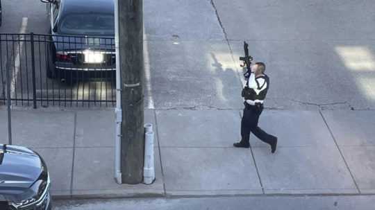 Policajt so zbraňou v ruke zasahuje počas streľby, ku ktorej došlo v budove banky v centre amerického mesta Louisville.