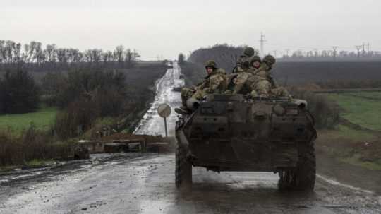 Ukrajinskí vojaci sedia na vojenskom obrnenom vozidle.