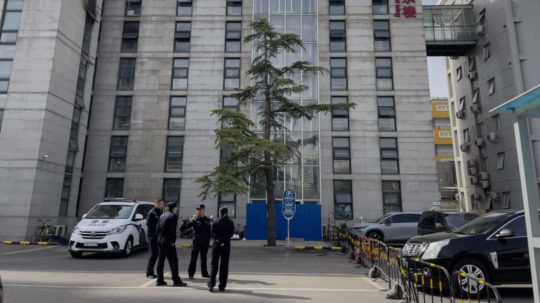 Policajti stoja pred budovou nemocnice v Pekingu.