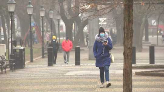 Ľudia s rúškami na tvári kráčajú po ulici.