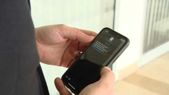 Osoba na snímke sa pozerá na obrazovku telefónu s podvodnou SMS.