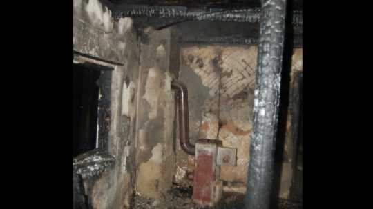 Na snímke zhorené vnútro domu, v strede liatinová pec.