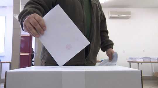 muž vhadzuje volebný lístok do urny