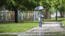 Na snímke žena s dáždnikom kráča počas dažďa v bratislavskej mestskej časti Ružinov.