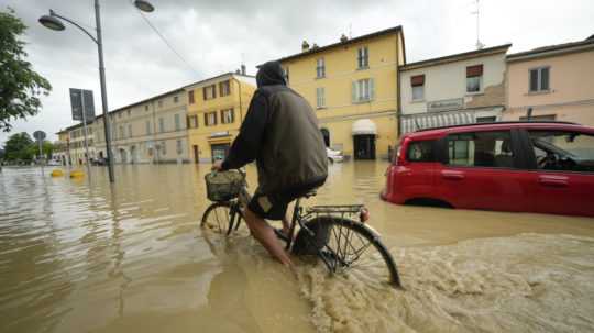 Cyklista sa brodí cez zaplavenú ulicu v obci Castel Bolognese v severotalianskom regióne Emilia Romagna.
