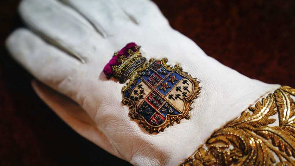 Biela kožená korunovačná rukavica s erbom vystavená v Buckinghamskom paláci.
