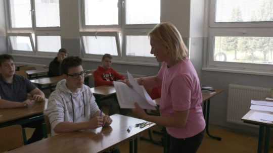 Na snímke učiteľka rozdáva žiakom hárky papiera