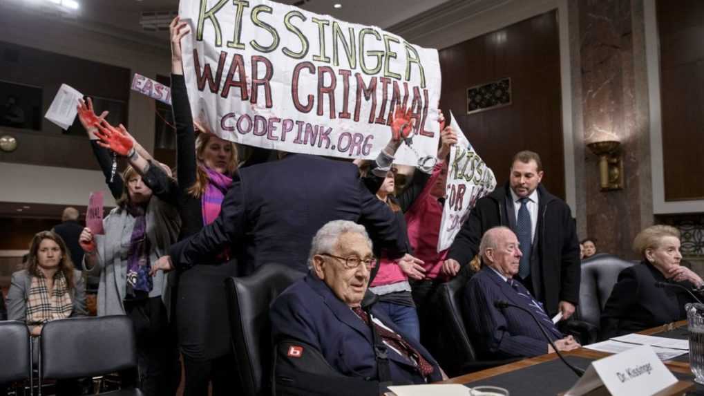 Protestujúci prerušujú začiatok rokovania Senátu v roku 2015, kričia na bývalého ministra zahraničných vecí Henryho Kissingera.