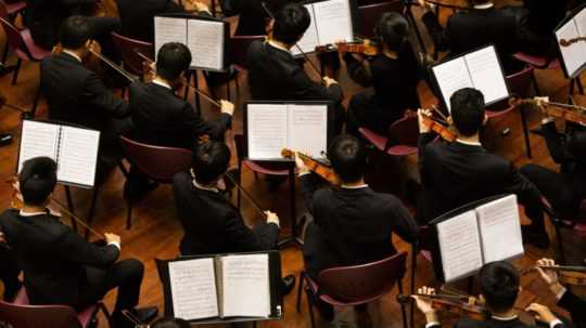 Na snímke sú huslisti v orchestri.