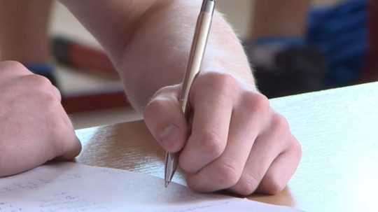 Na snímke žiak píše perom.