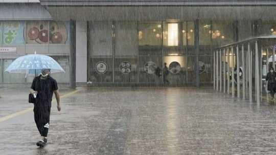 Muž kráča v silnom daždi počas príchodu tajfúnu Mawar v japonskom meste Koči.