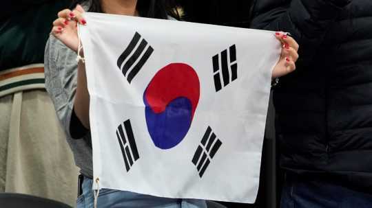 Na snímke žena drží vlajku Južnej Kórey.