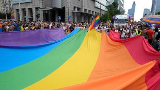 Ľudia nesú dúhovú vlajku počas každoročného sprievodu hrdosti, známeho ako Pochod za rovnosť, vo Varšave v Poľsku v sobotu 17. júna 2023.